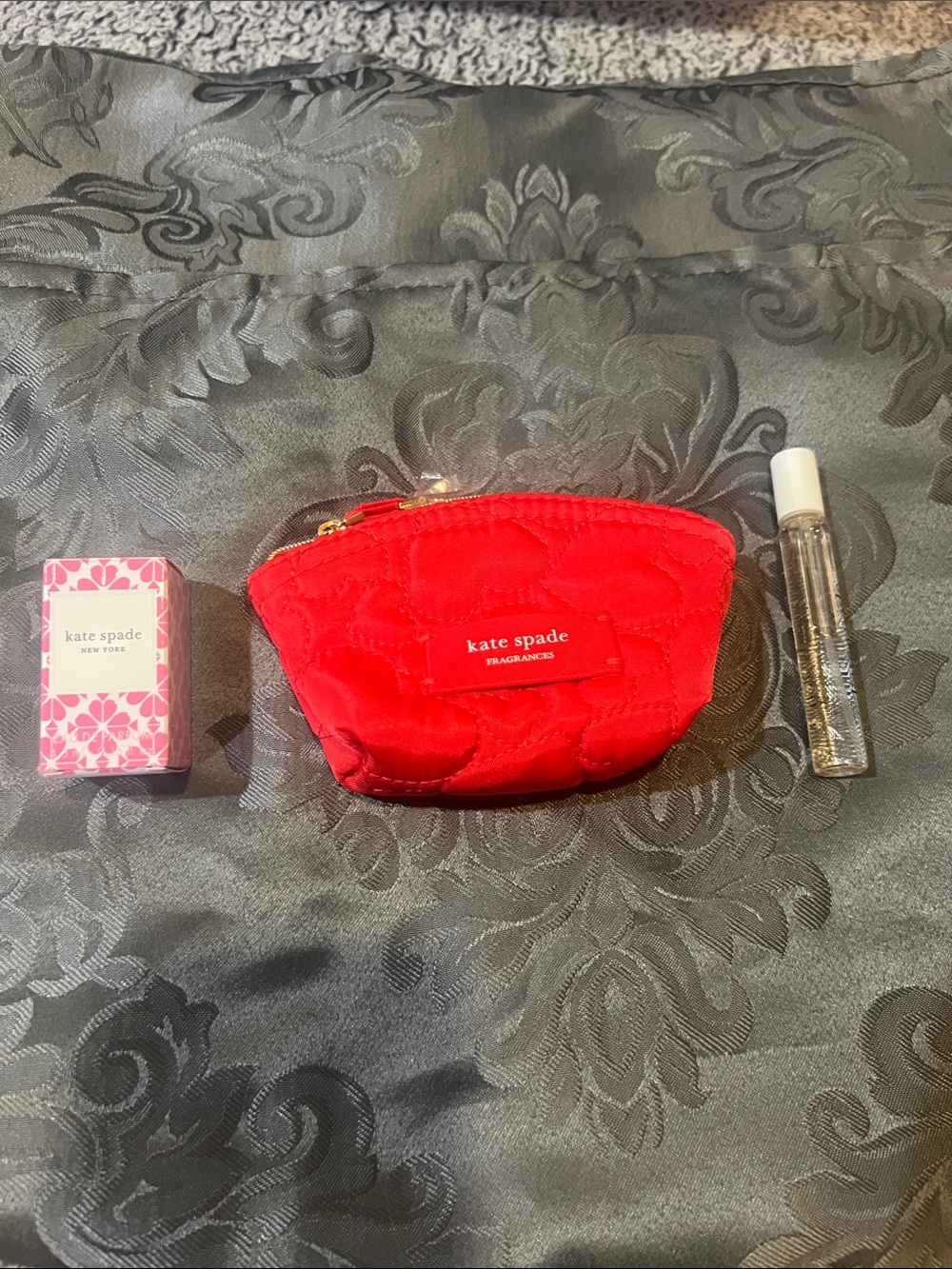 kate spade red quilted pouch with gold zipper pull and two fragrance samples